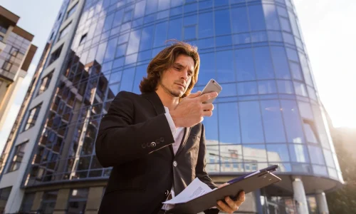 businessman-using-his-phone-front-building